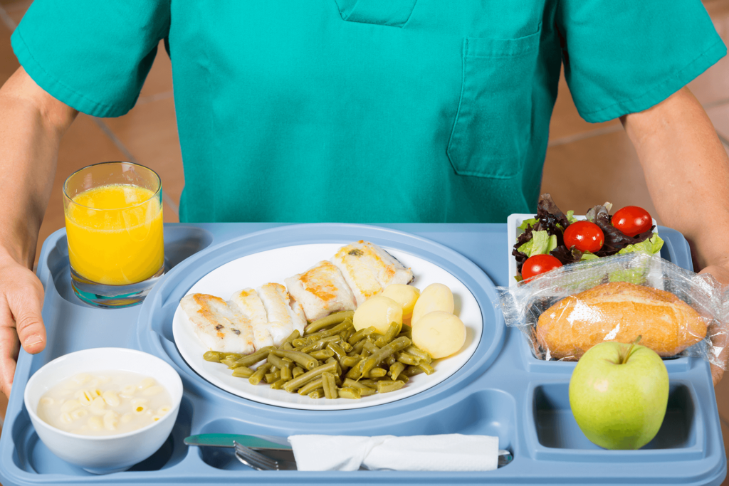 person in scrubs holding a hospital food tray, healthcare
